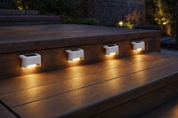 Path solar deck lights on rustic walnut stairs at twilight